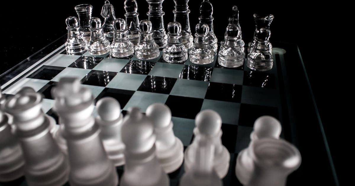Glass chess board with pieces representing strategic game theory concepts