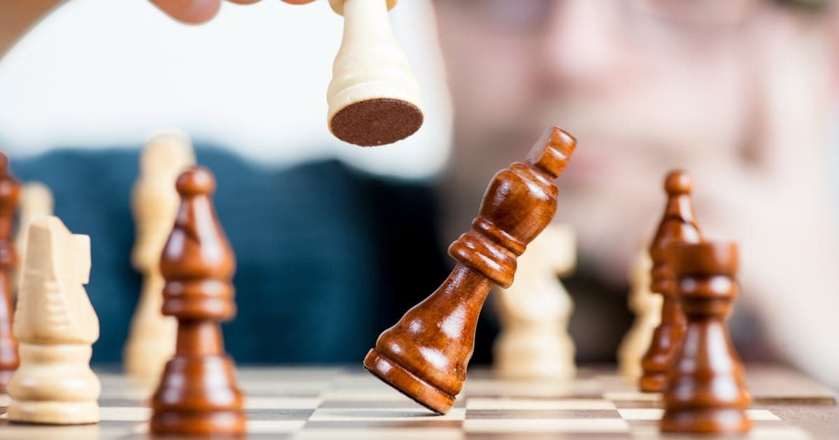 Person holding a chess piece mid-move representing strategic thinking